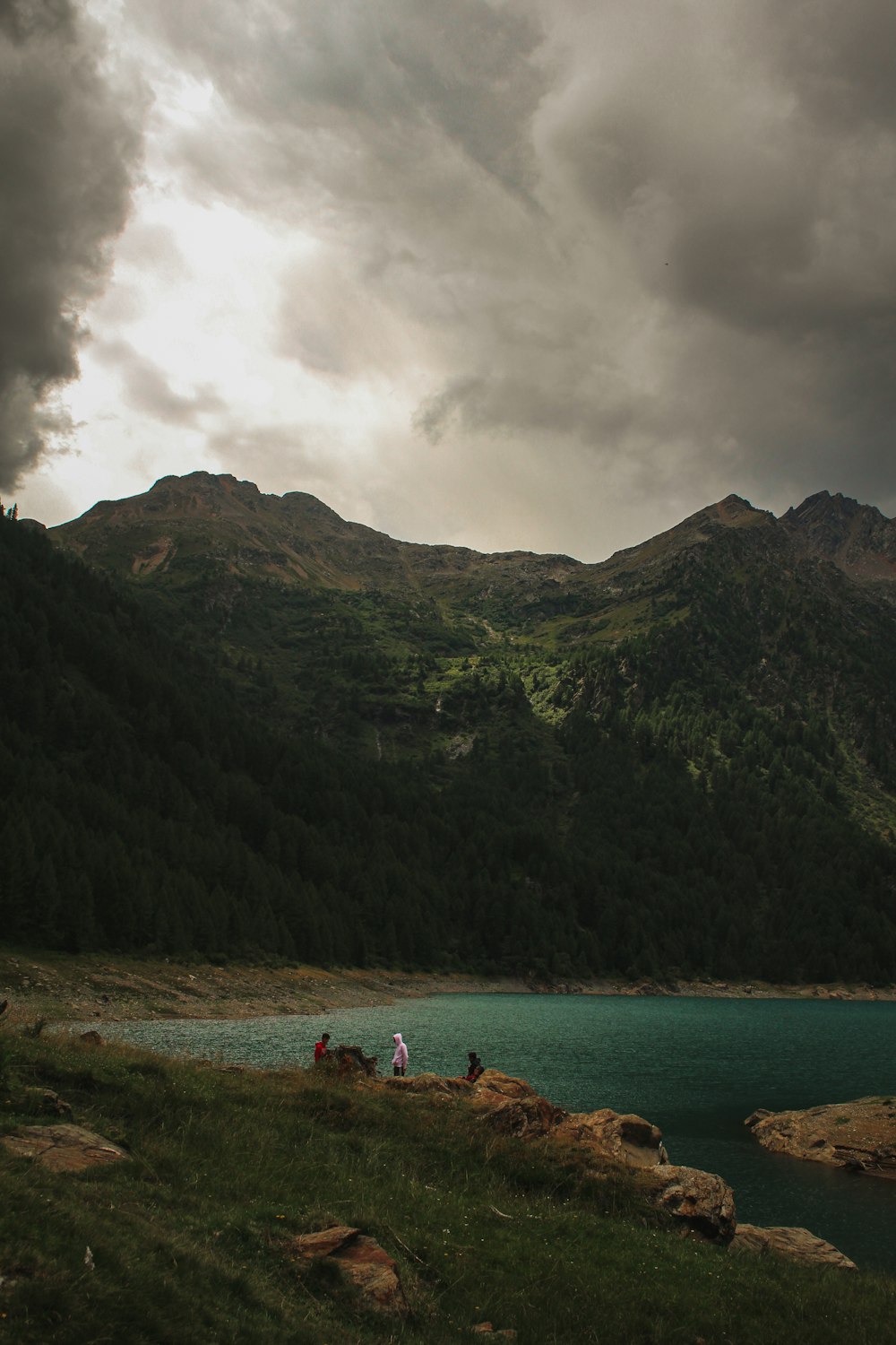 a group of people standing on a rocky shore by a body of water