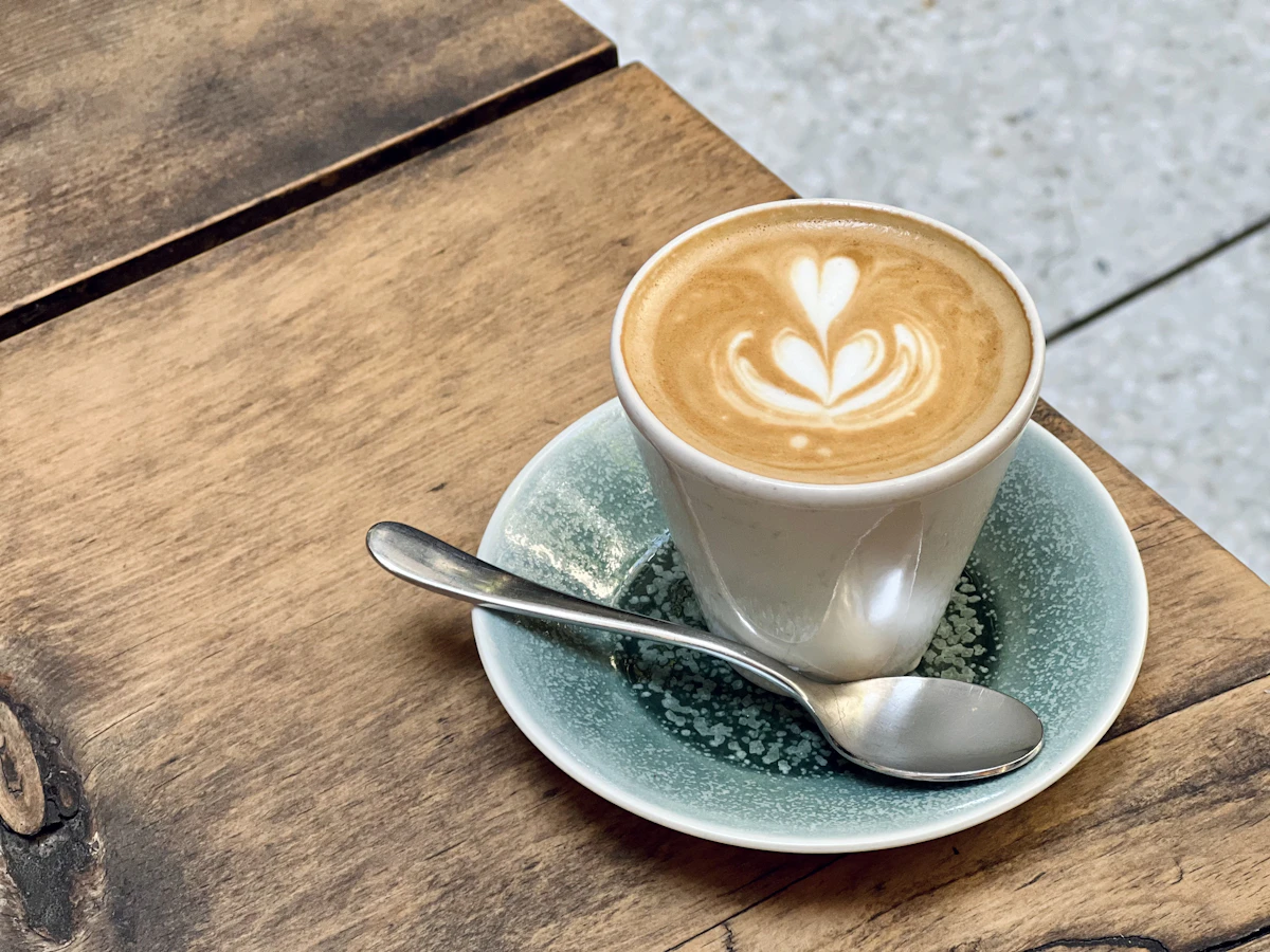 Ly cà phê đặc sản với lớp bọt latte art trên bàn gỗ