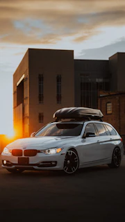 A family loading their gear into a roof box on a sunny day.