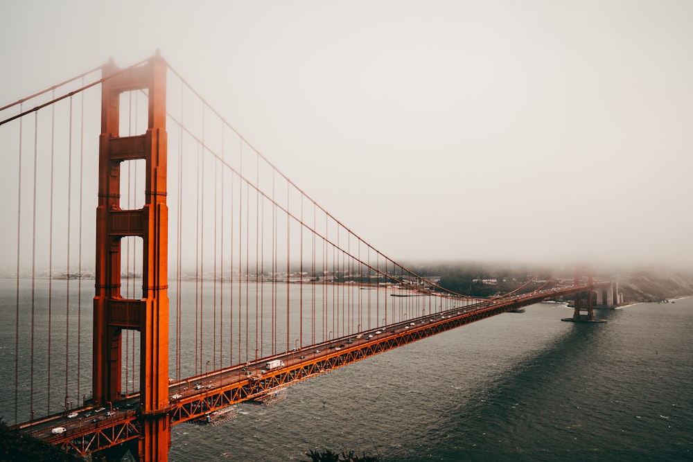 a large red bridge over water with Golden Gate Bridge in the background