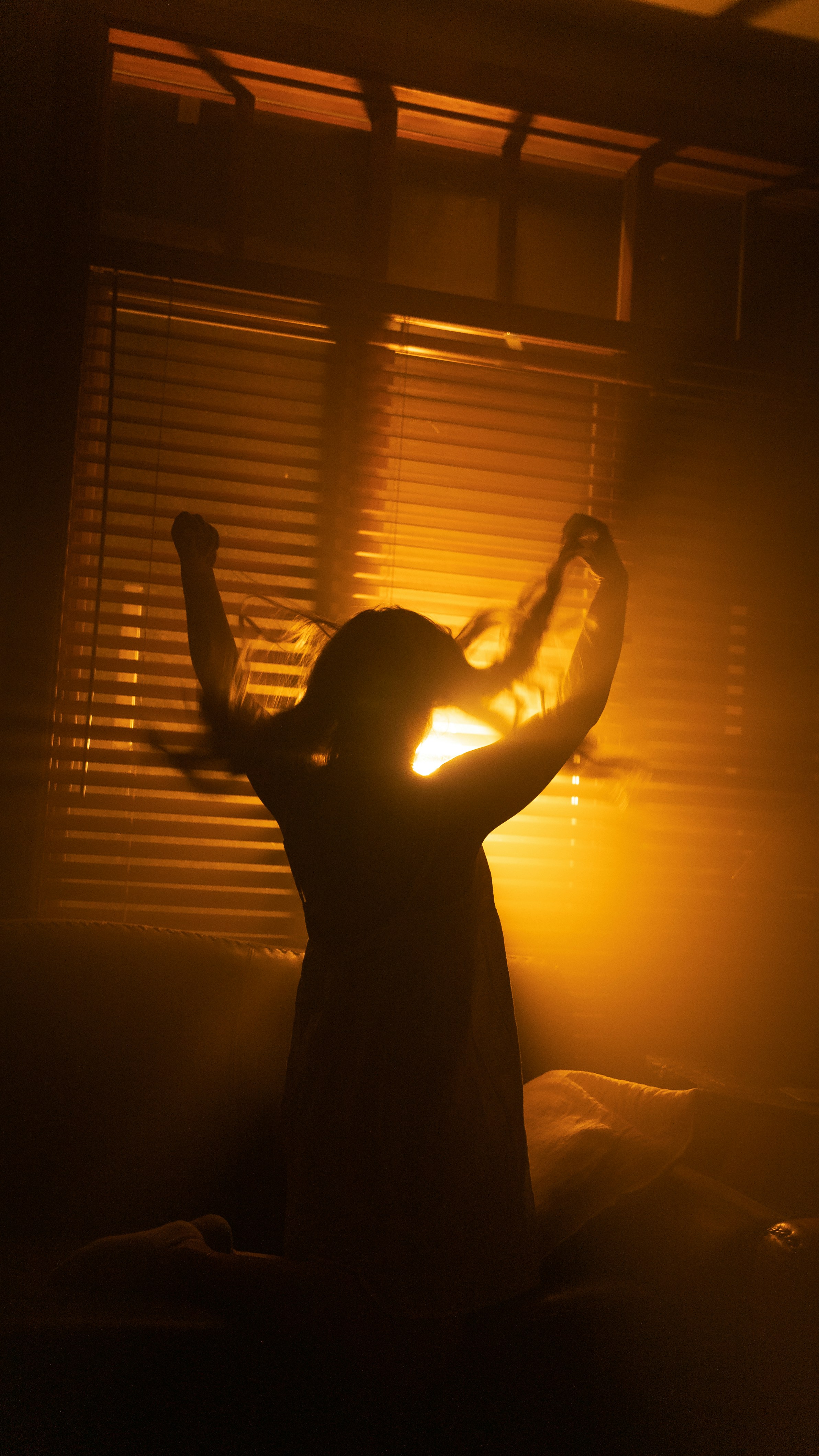 Eine Person, die mit erhobenen Armen vor einem Fenster steht