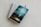 A spiral-bound notebook with lined pages lies open on a light-colored surface. A pen rests on top of the notebook. A book with a turquoise and green cover titled 'The Gifts of the Spirit' by Derek Prince is placed on top of the notebook.
