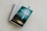 A spiral-bound notebook with lined pages lies open on a light-colored surface. A pen rests on top of the notebook. A book with a turquoise and green cover titled 'The Gifts of the Spirit' by Derek Prince is placed on top of the notebook.