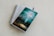 A spiral-bound notebook with lined pages lies open on a light-colored surface. A pen rests on top of the notebook. A book with a turquoise and green cover titled 'The Gifts of the Spirit' by Derek Prince is placed on top of the notebook.