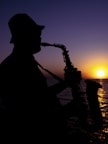 a silhouette of a man playing a saxophone at sunset