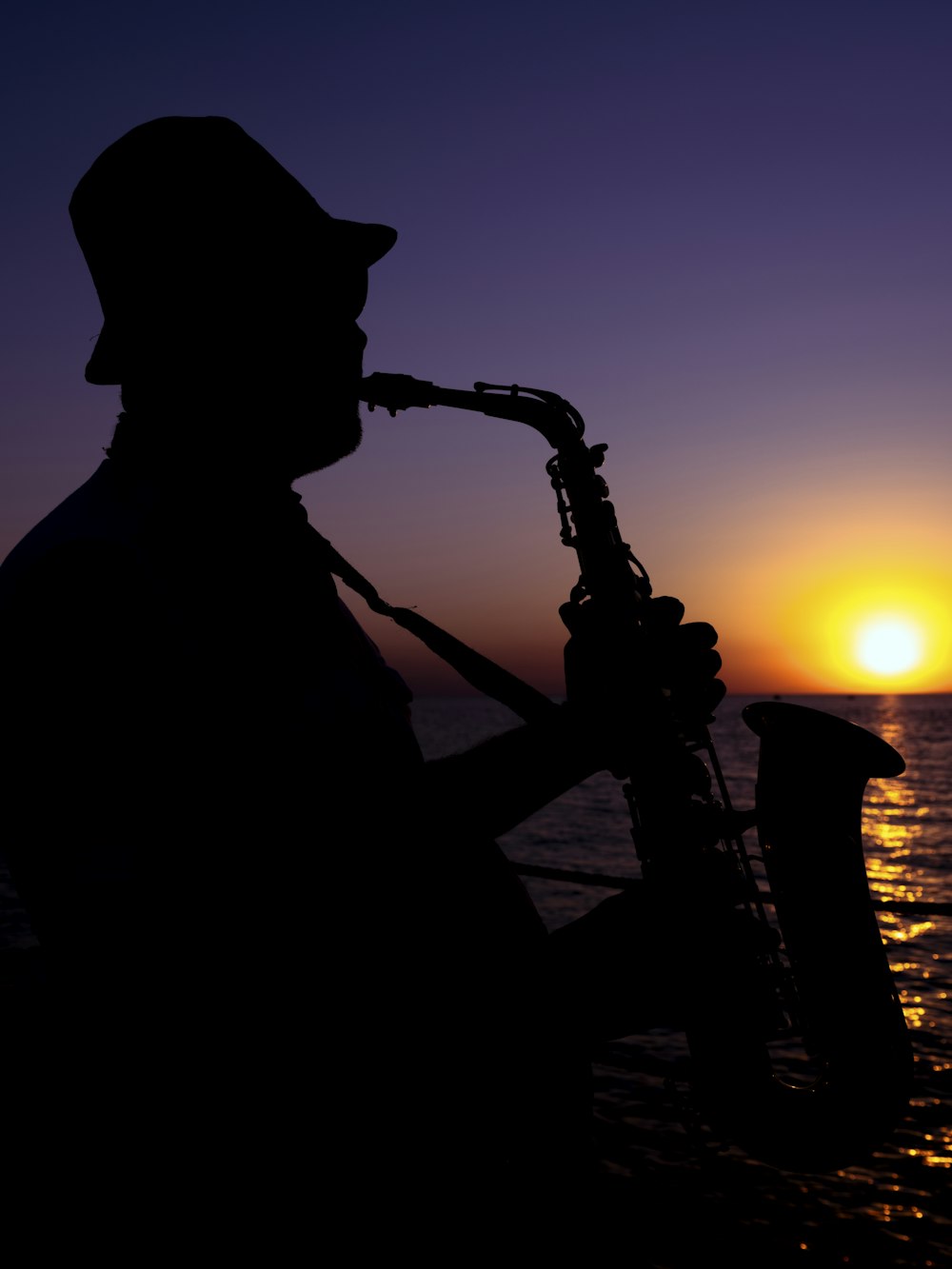 a silhouette of a man playing a saxophone at sunset