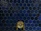 A wall covered with dark blue hexagonal tiles, featuring a central antique brass faucet with intricate handles.