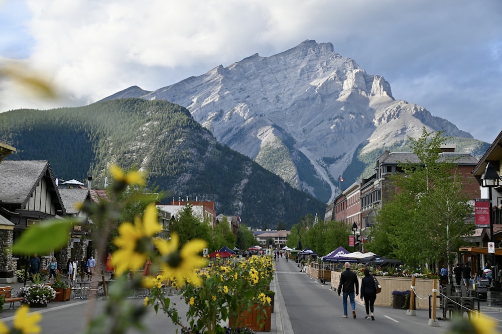 people walking on a street in front of a mountain