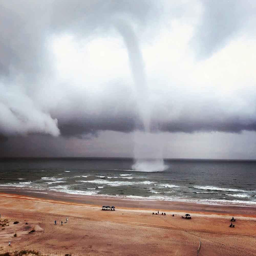 a beach with people and a body of water with a rainbow in the sky