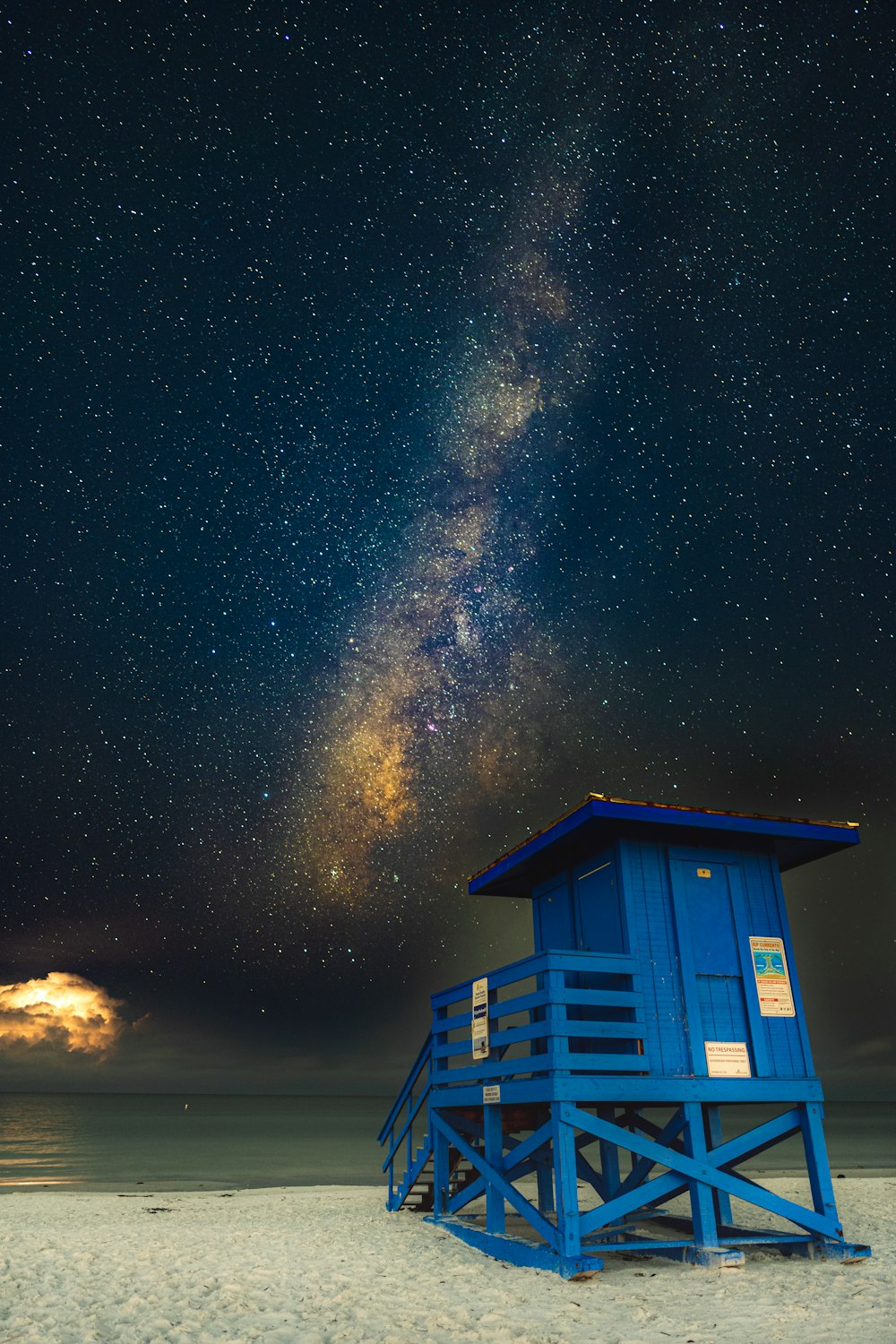 a blue shack on a beach with stars in the sky