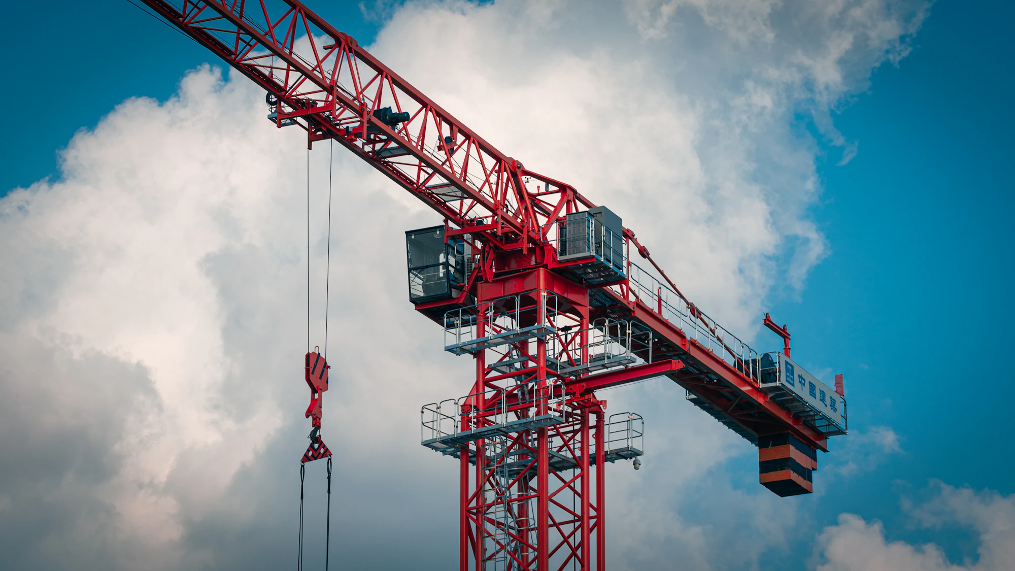 Red tower crane against clouds