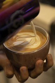 Elegant latte art being poured into a ceramic cup at an event.