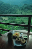Guests enjoying tea on the wooden veranda overlooking rice fields.