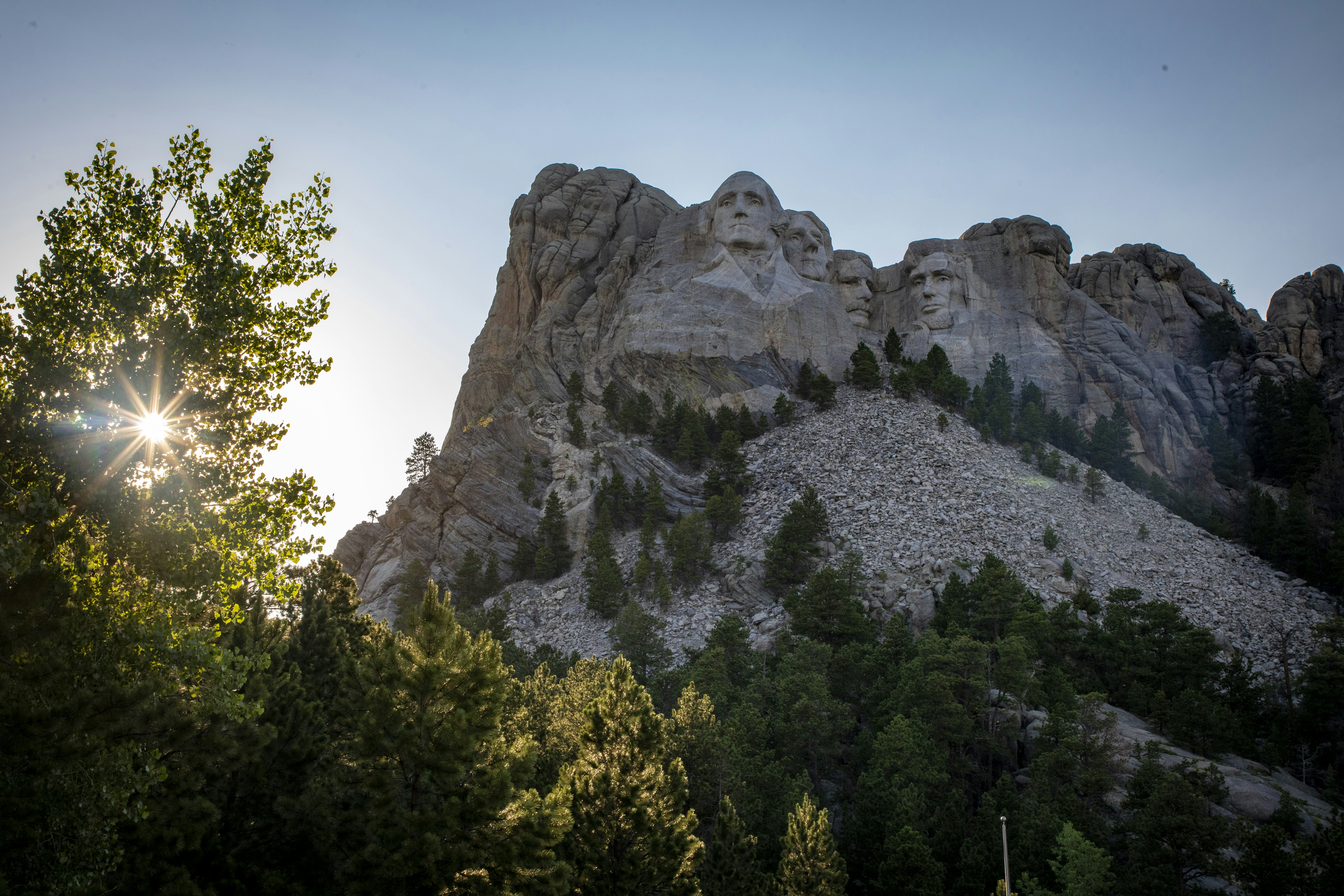 a rocky mountain with trees below