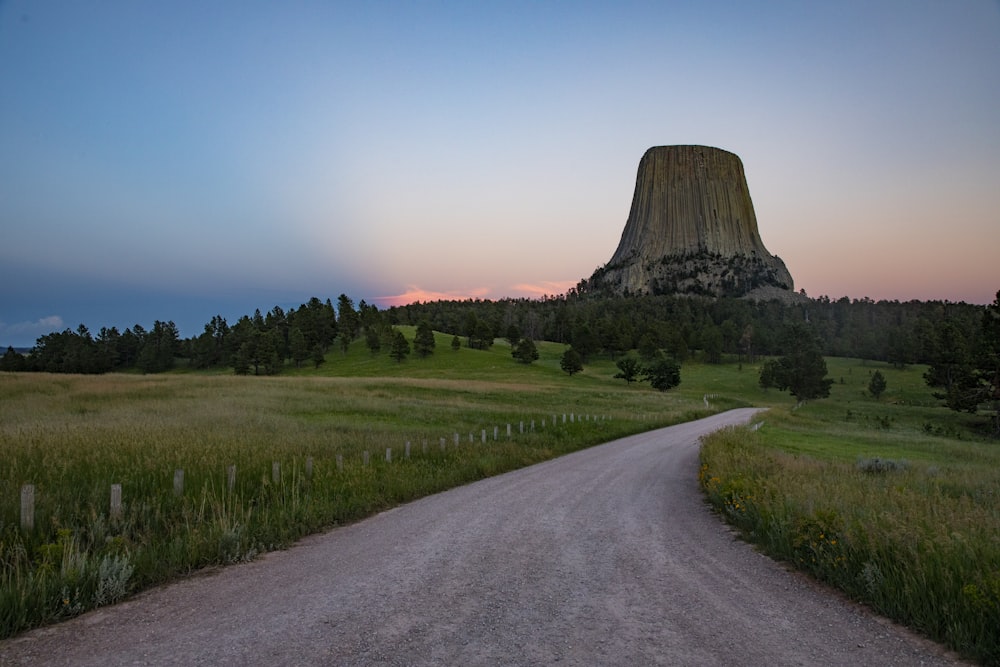 a road leading to a pyramid with Devils Tower in the background