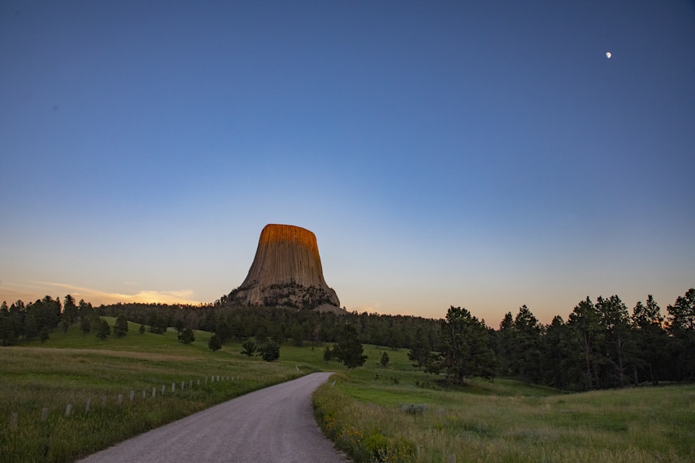 a road leading to a pyramid with Devils Tower in the background