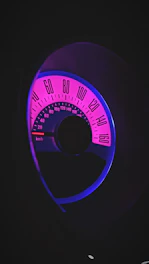 A sleek digital speedometer glowing with electric cyan light against a deep obsidian background.