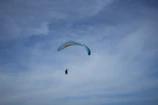 A tandem paraglider soaring high above the rugged Atlas Mountains with clear blue skies.