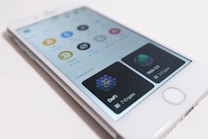 A smartphone displays a cryptocurrency app interface with logos of different cryptocurrencies like Bitcoin, Dogecoin, and Stellar. The app includes sections for various collections like DeFi and Web 3.0, with the number of cryptos listed under each.