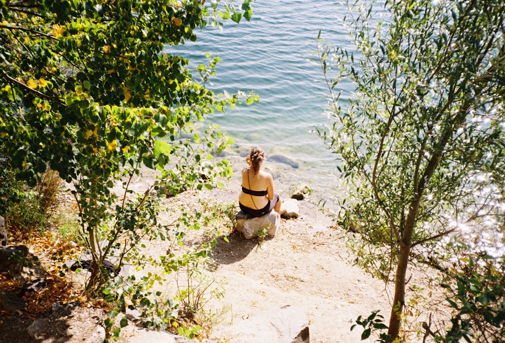 a person sitting on a rock by the water