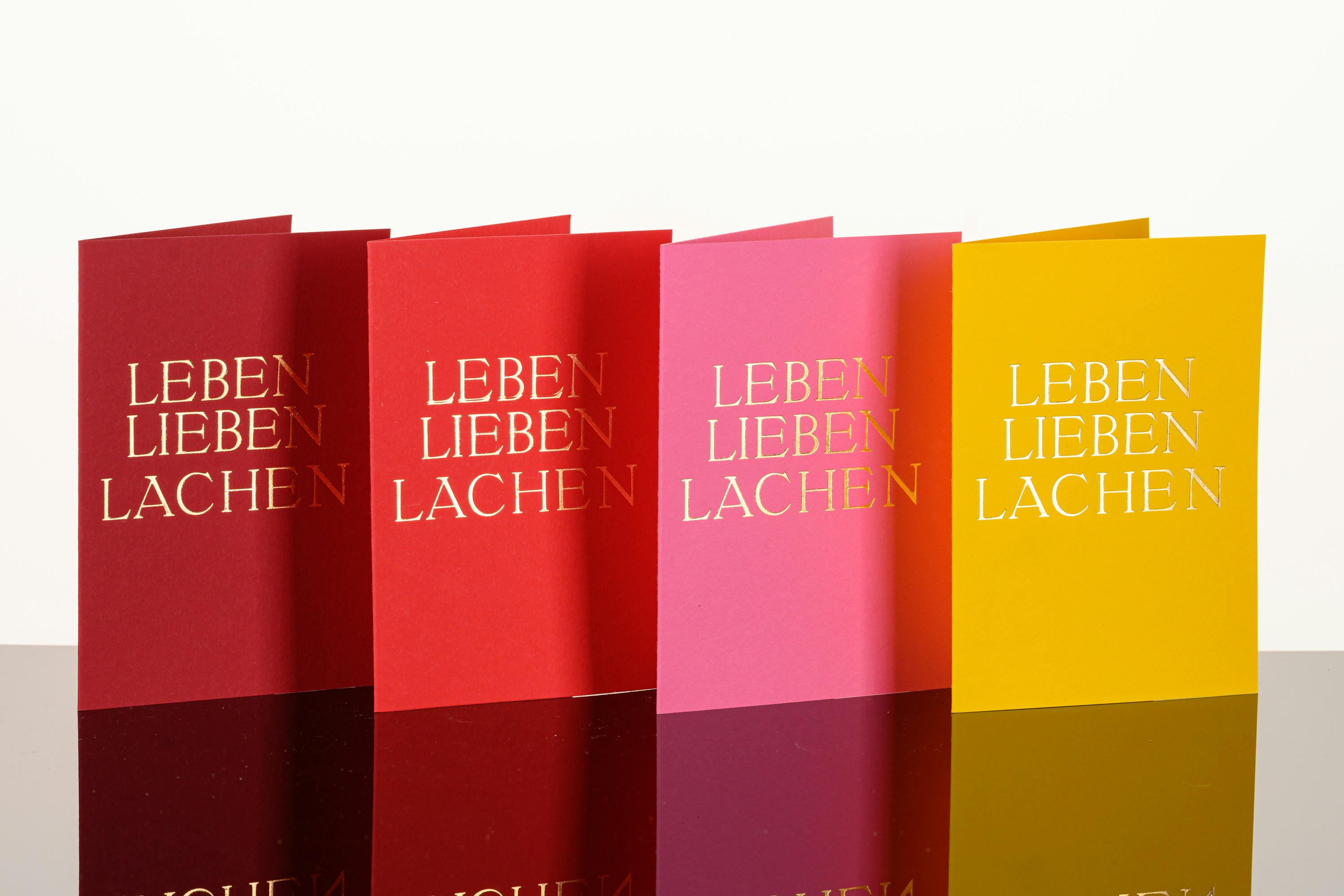 Stack of colorful holiday greeting cards with snowflake designs and gold foil accents