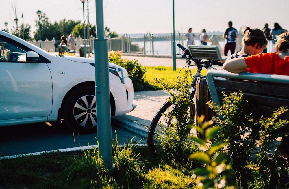 a car parked on the side of a road with people and a bike