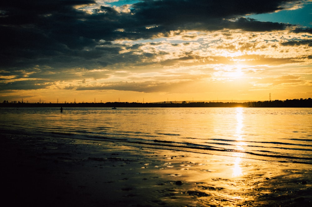 a body of water with a cloudy sky above it