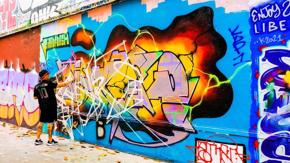 a person standing next to a wall with graffiti