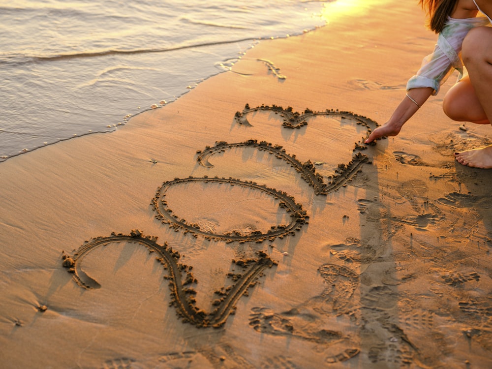 a person drawing a heart in the sand