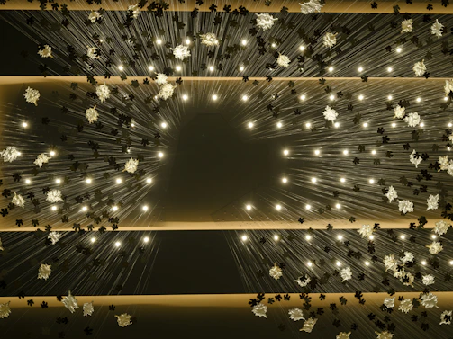 Decorative aerial installation featuring suspended flowers and delicate champagne gold lamps