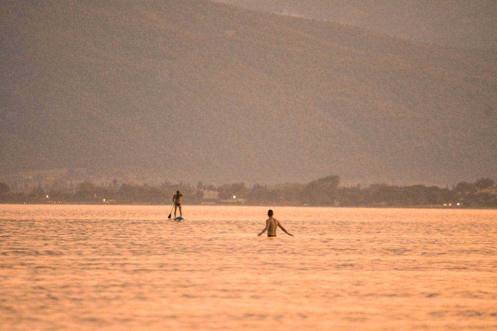 a couple people walking in a lake