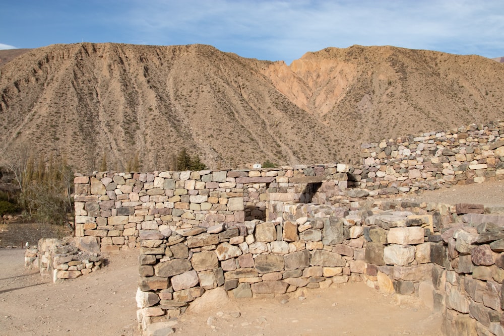 a stone wall in front of a mountain