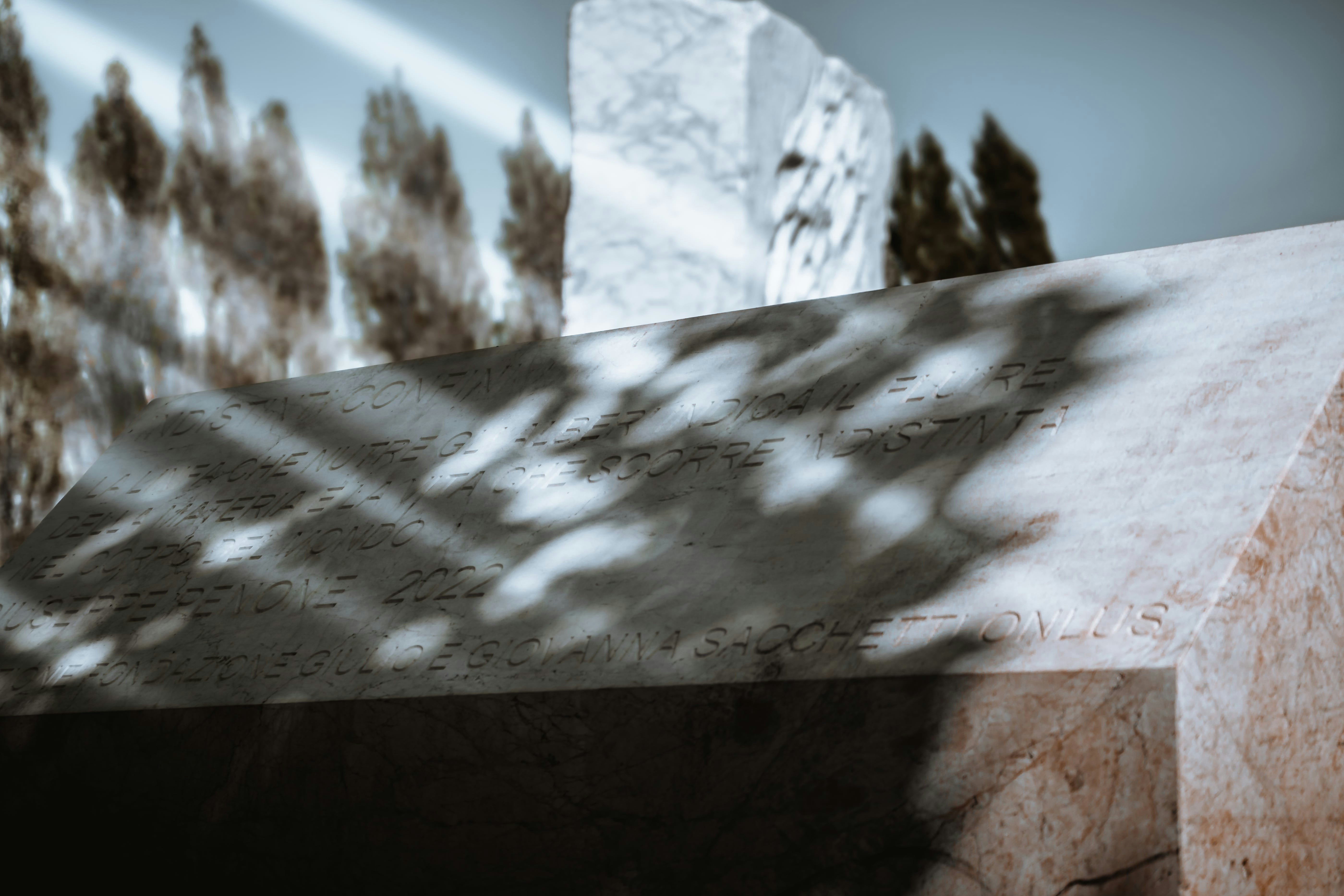 Testo italiano scolpito su un monumento di marmo bianco e rosa.