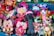 A collection of colorful handmade dolls and stuffed animals displayed together. The dolls are dressed in vibrant traditional attire, featuring bright colors and patterns. Several plush llamas and other animals knitted in bright woolen textures are also present, creating a lively and festive appearance.