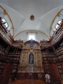 A serene seminary library corner with burgundy leather chairs and shelves filled with sacred texts.
