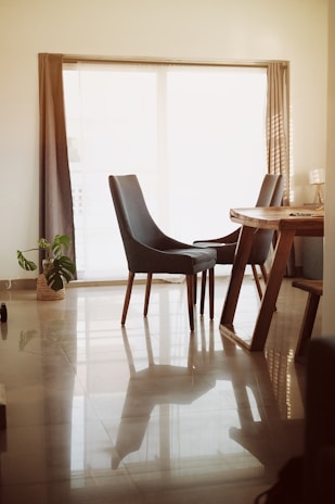 A sleek dining set with a polished wooden table and matching chairs arranged in a bright dining area.