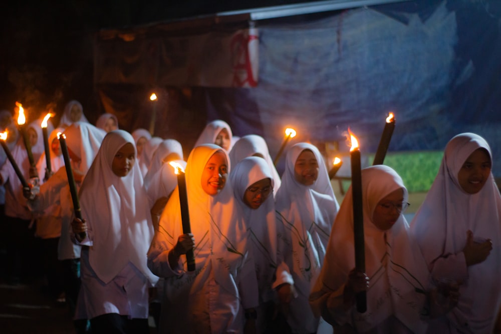 a group of people wearing white robes holding candles
