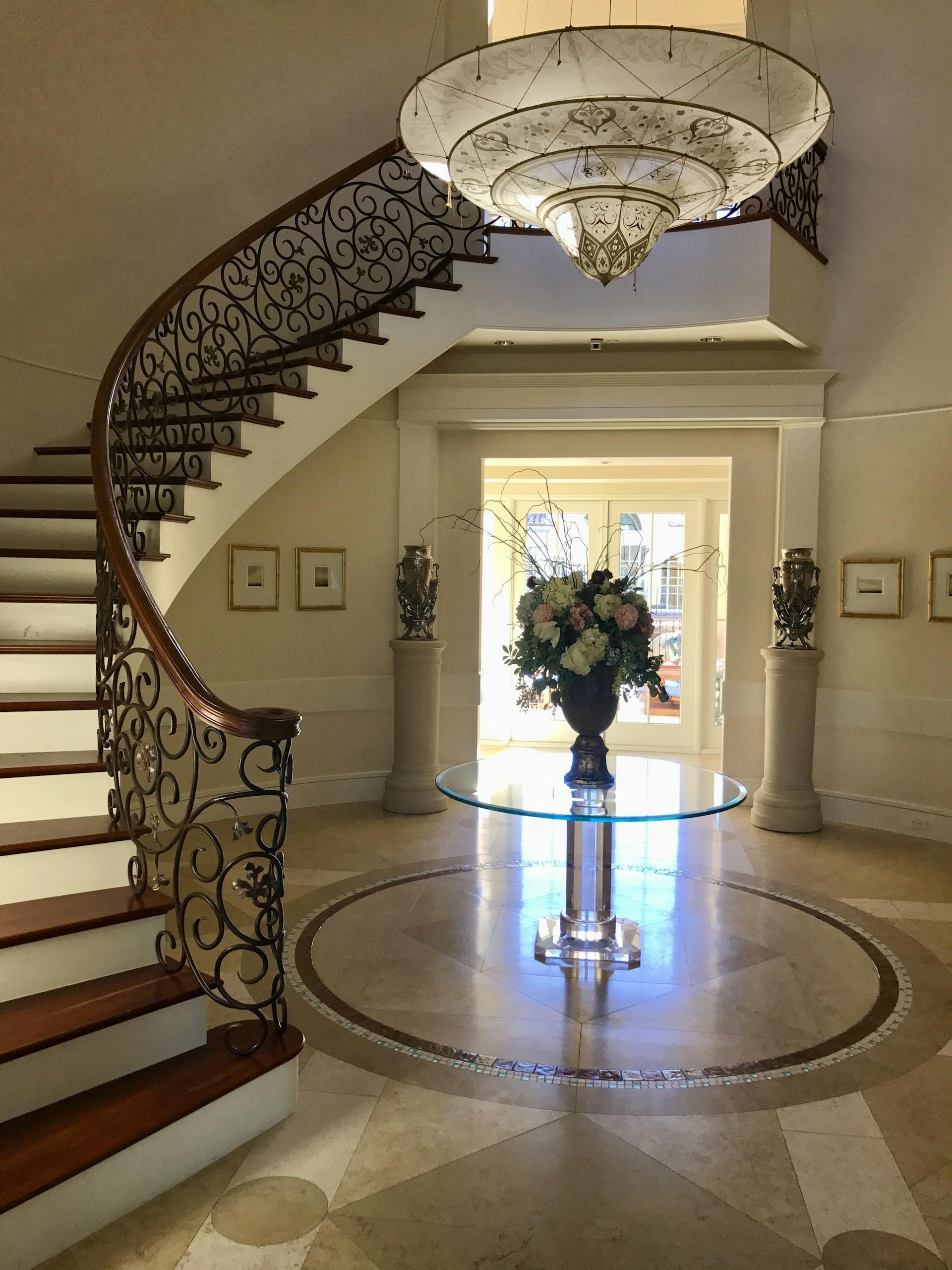 a staircase with a glass table and a vase with flowers on it