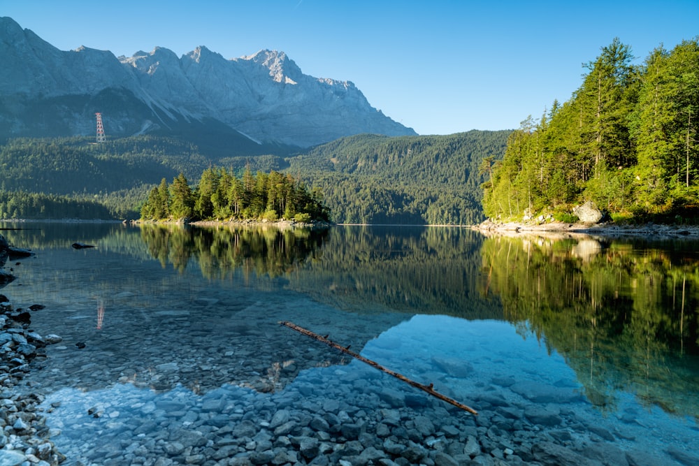 a lake with a rocky shore and trees and mountains in the background