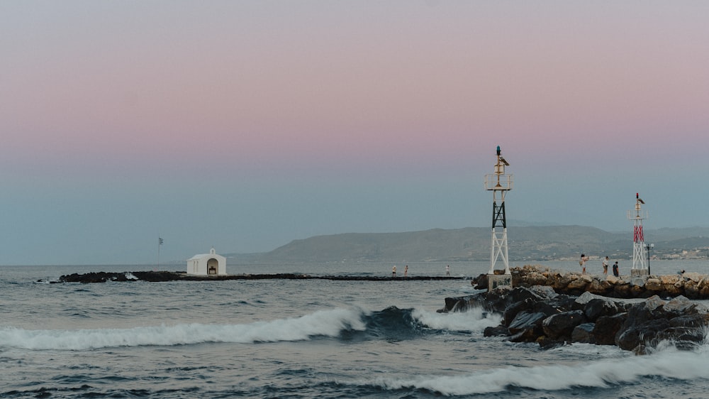 a group of people on a rocky beach with a lighthouse in the distance