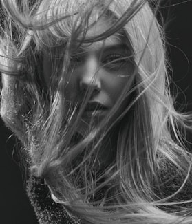 A striking black and white portrait of a woman with natural light highlighting her expression