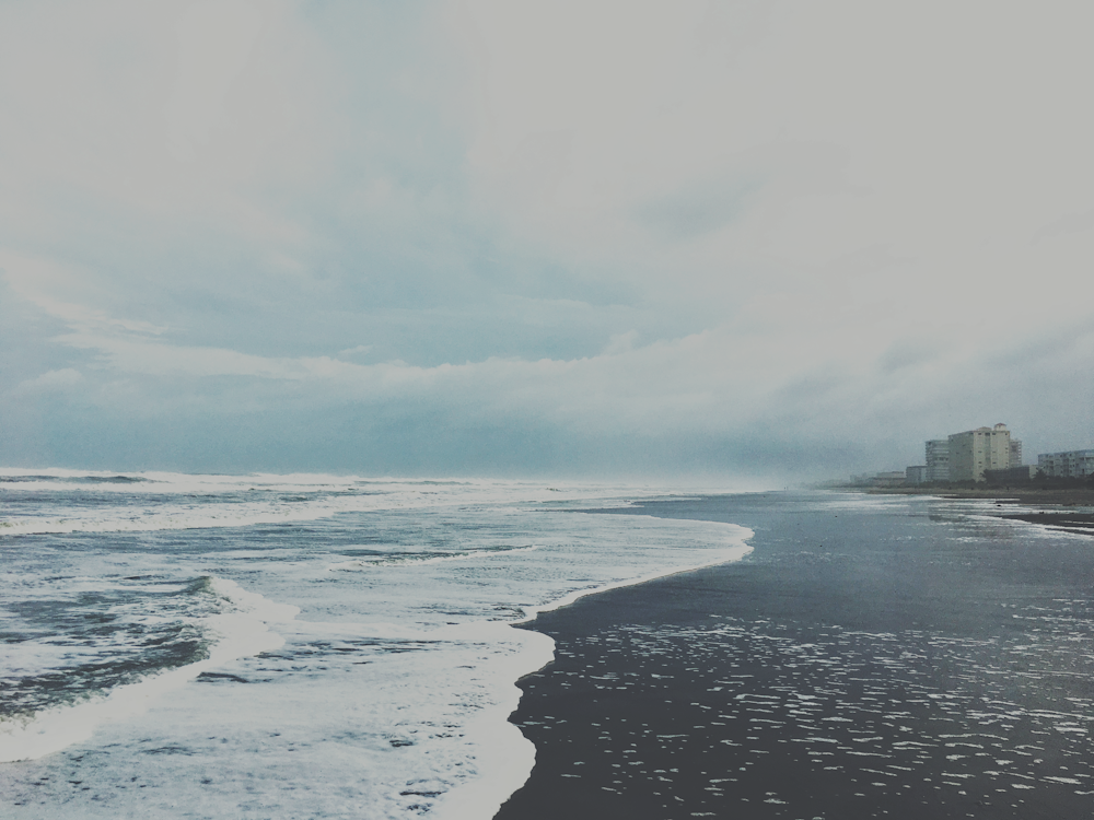 a beach with waves and buildings in the background