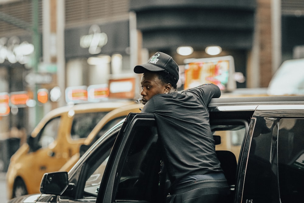 a person in a hat and jacket sitting in a car