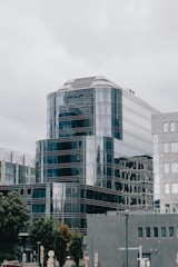 Sleek office building with reflective glass facade surrounded by greenery.