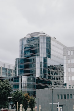 Sleek office building with reflective glass facade surrounded by greenery.