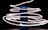 A cylindrical blue speaker stands in the center, surrounded by swirling trails of bright white light against a dark background. The light streaks create a dynamic and futuristic effect, as if wrapping around the speaker.