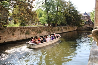 Group of happy tourists enjoying a boat ride on a calm river surrounded by lush greenery.