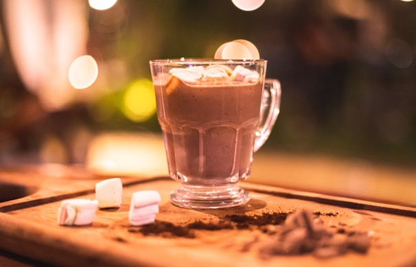 A close-up of a hot chocolate bomb melting in a steaming mug, releasing cocoa and marshmallows.
