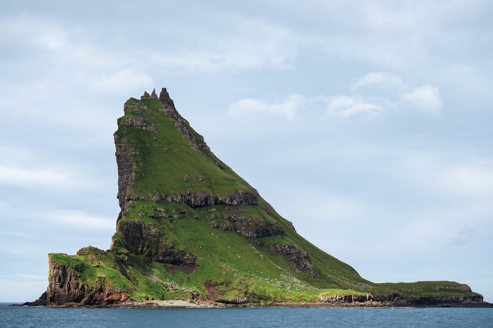 Ein grüner Hügel mit einem Gebäude darauf am Wasser