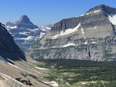 A snow-streaked peak above a green valley in Glacier National Park